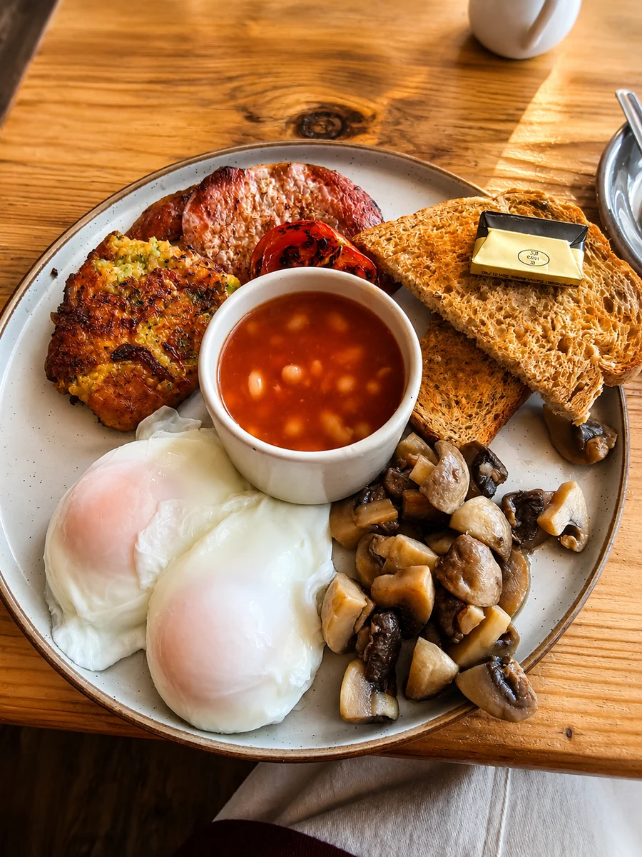 A cooked breakfast with eggs, toast, beans and mushrooms